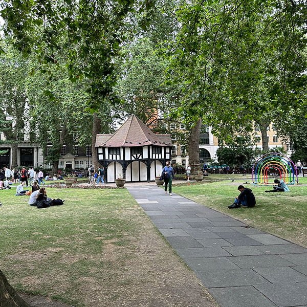Visitors relaxing on benches in Soho Square's tranquil garden setting
