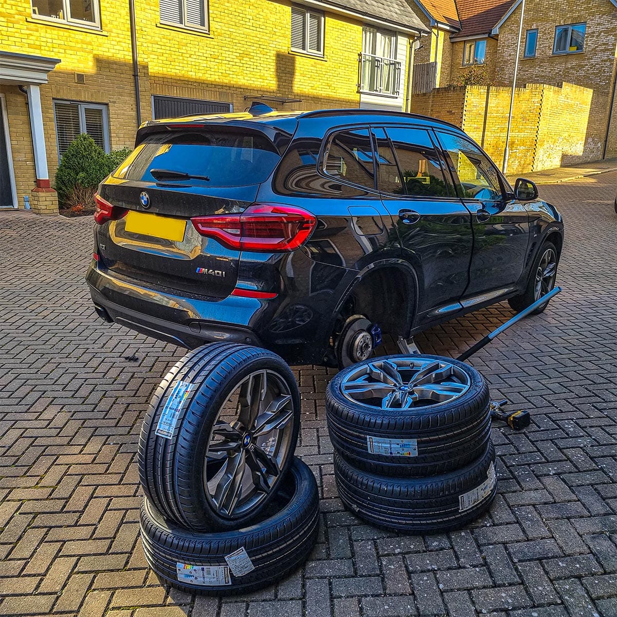 On-site tyre fitting service Mobile tyre technician fitting new tyre to vehicle at customer's home location