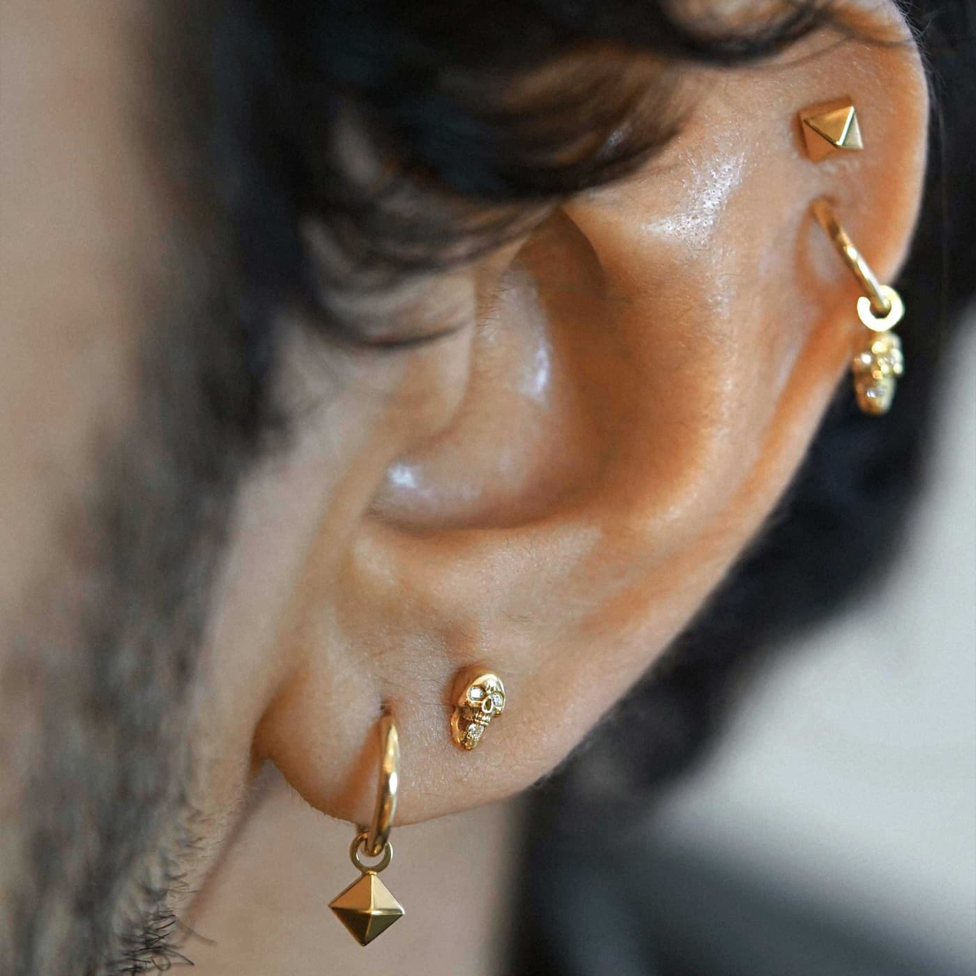 Stacked ear styling jewellery Curated ear stack featuring multiple 18k gold studs and hoops demonstrating Soho street style