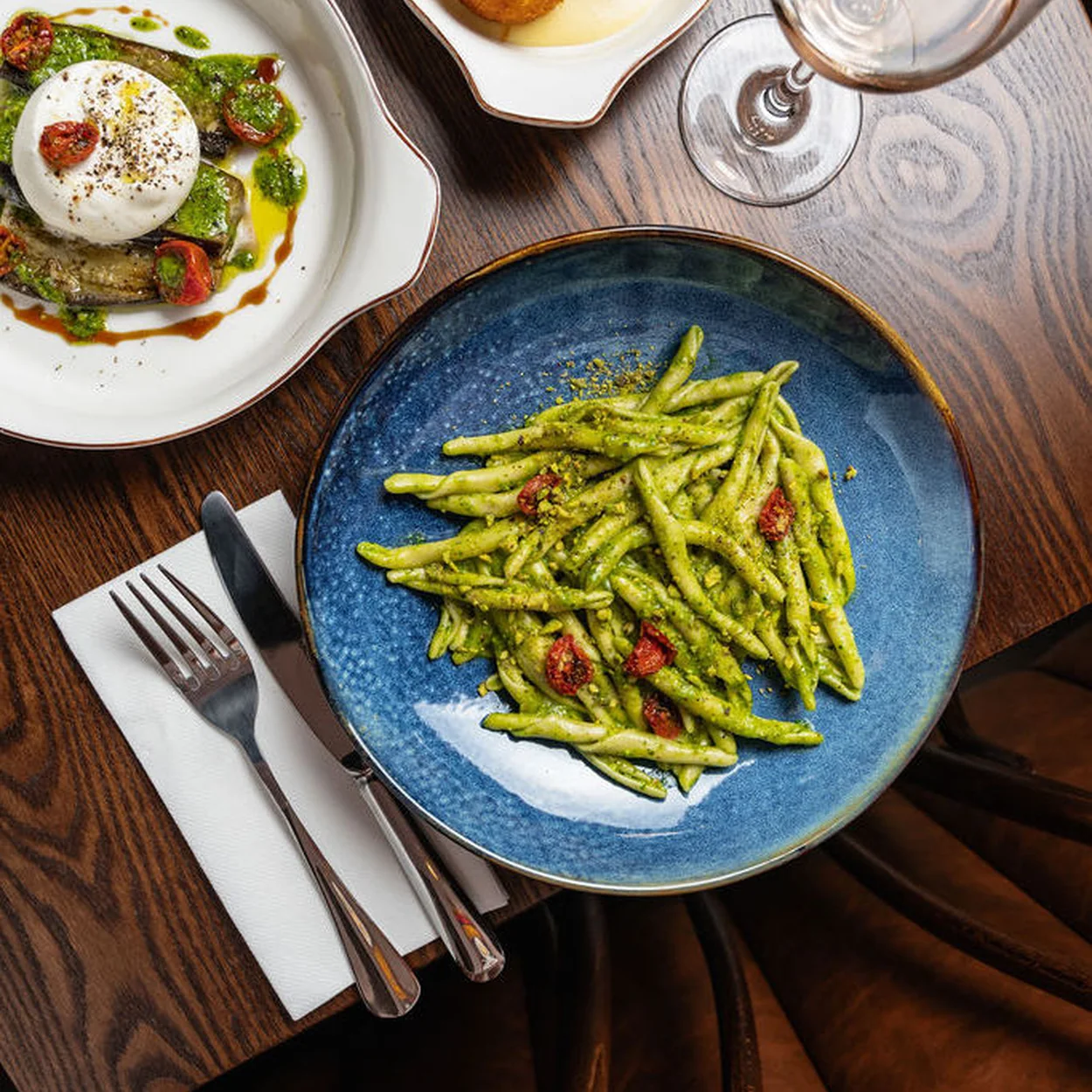 Overhead plates of green beans, arancini and burrata on blue crockery at 27 Old Compton Street