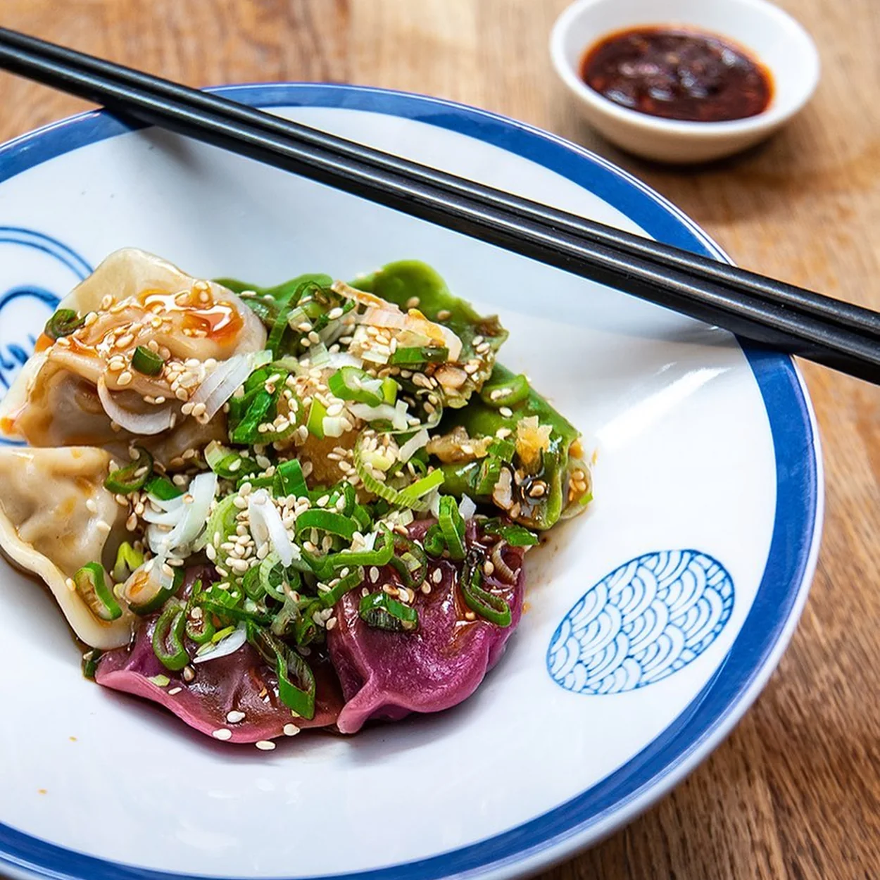 Tricolour dumplings with sesame and chilli oil on Baozi Inn's blue-rimmed plate
