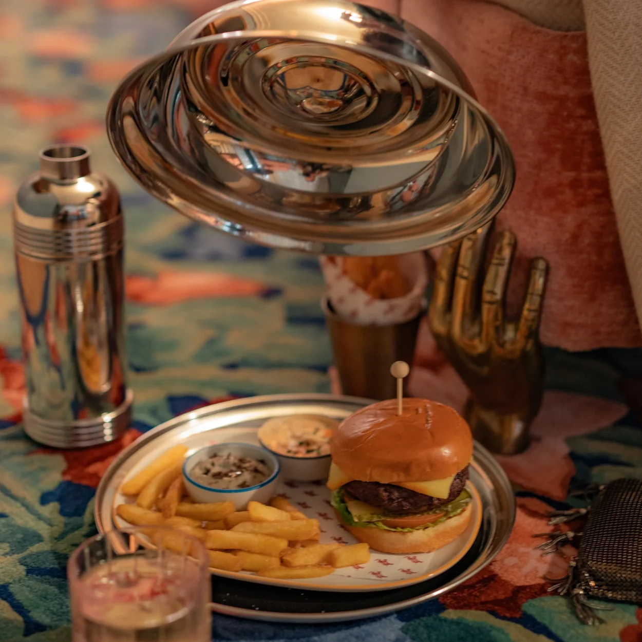 Burger, fries and a cocktail served on a silver tray at Bar Jackie inside Broadwick Soho