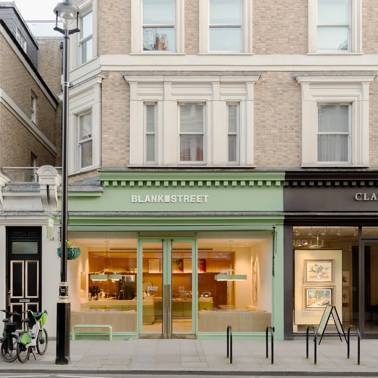 Blank Street Coffee's signature sage-green shopfront on a classic London parade