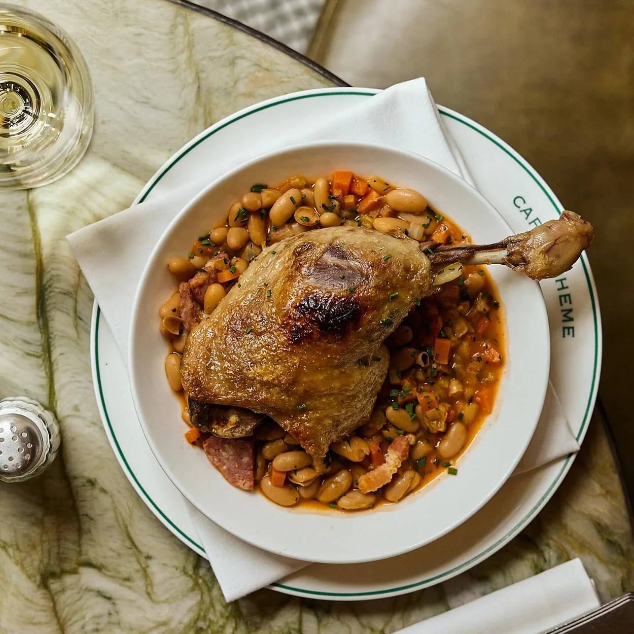 Confit duck leg with white beans served on Cafe Boheme's crested plate