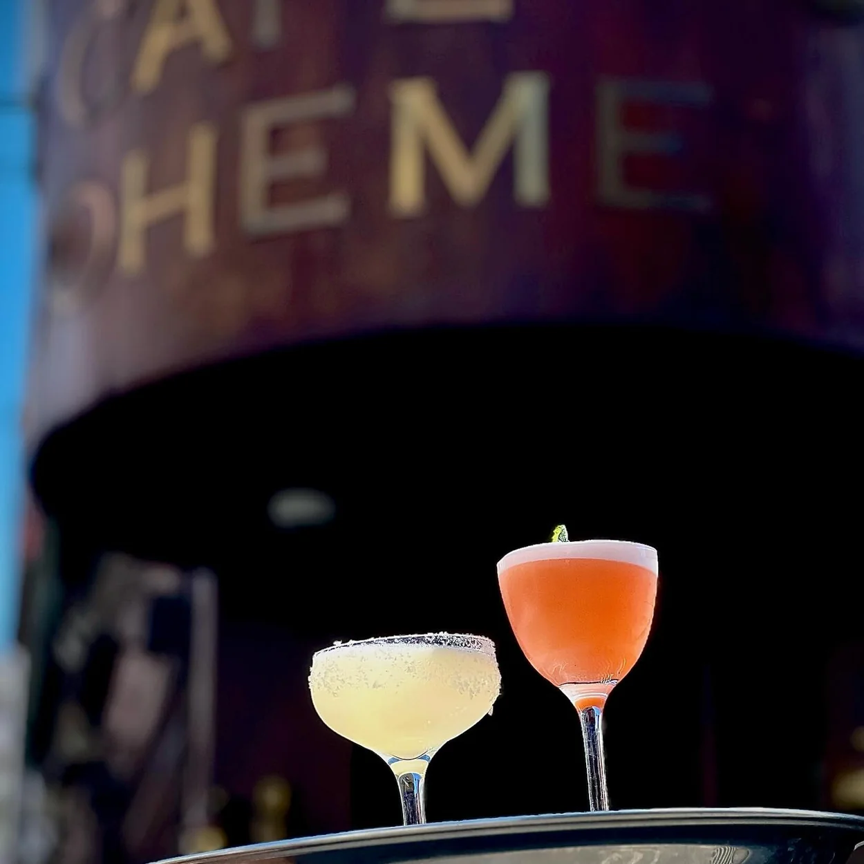 Waiter's tray of cocktails in front of the Cafe Boheme sign on Old Compton Street