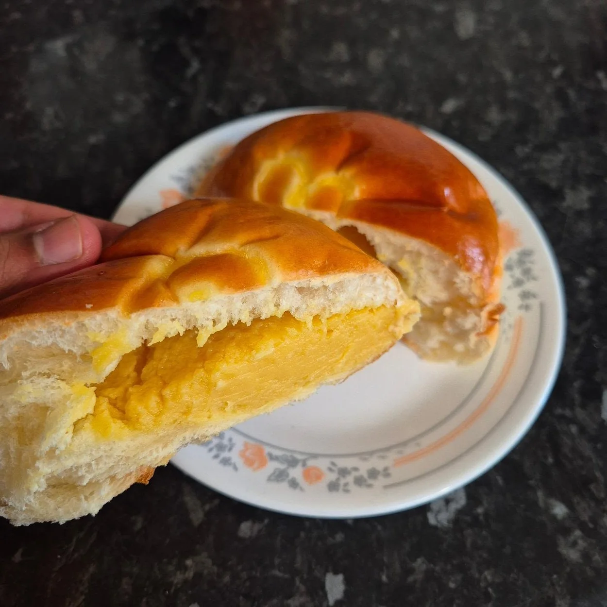 Golden custard bun halved on a plate at Chinatown Bakery in London