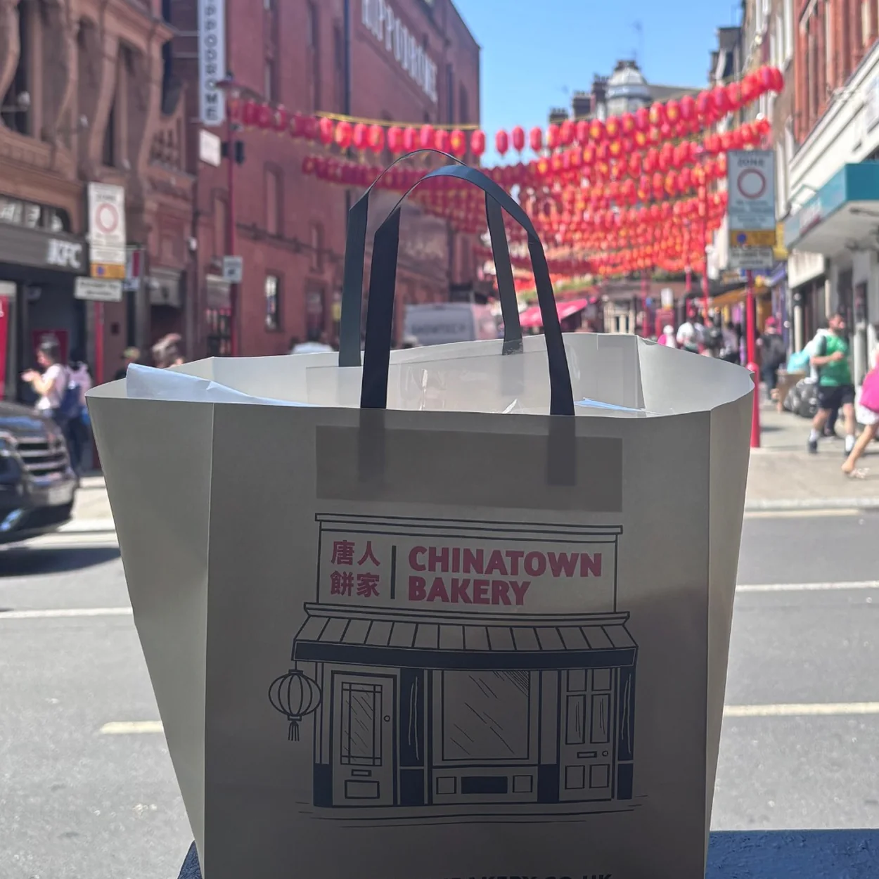 Chinatown Bakery paper bag carried under the red lanterns of Gerrard Street