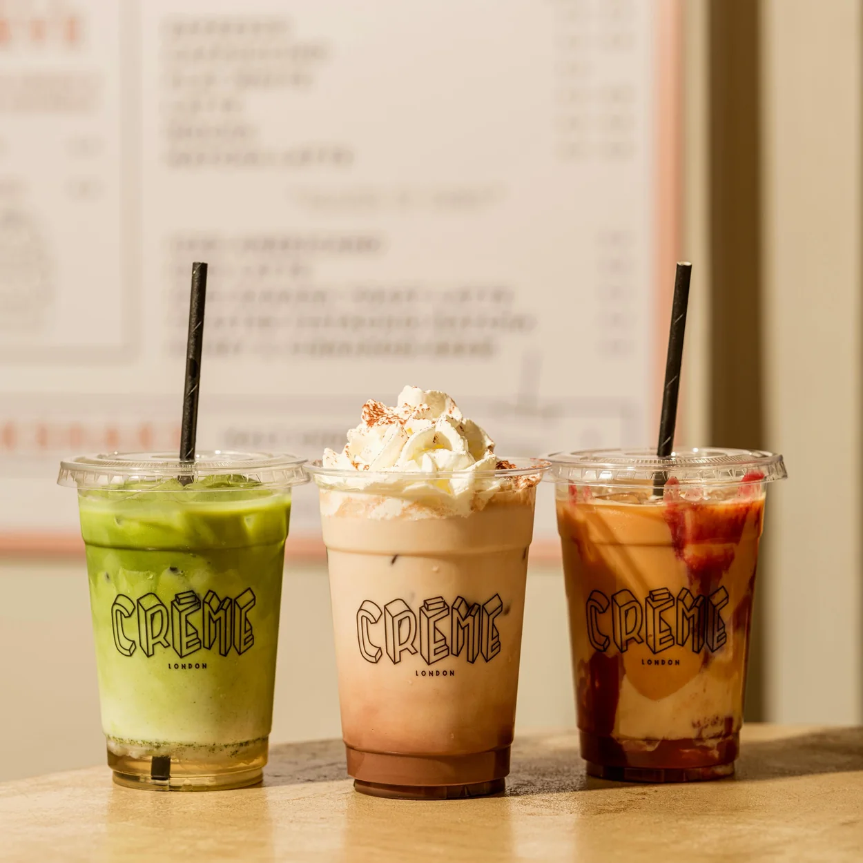 Iced matcha, shake and coffee lined up on the counter at Creme in Soho