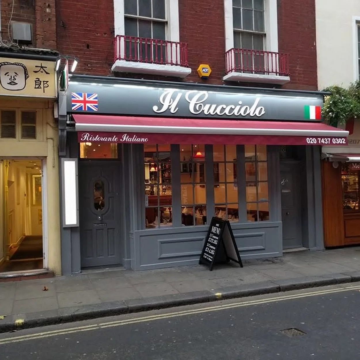 Il Cucciolo's grey and white frontage with tricolore flashes on Old Compton Street
