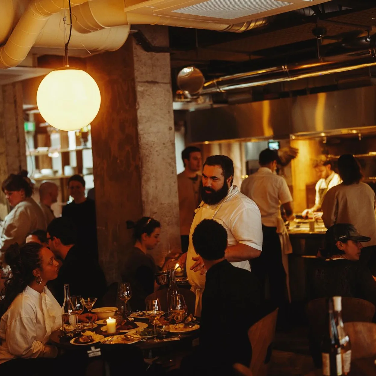 Dining room and open kitchen in full service at Impala, the live-fire restaurant in Soho