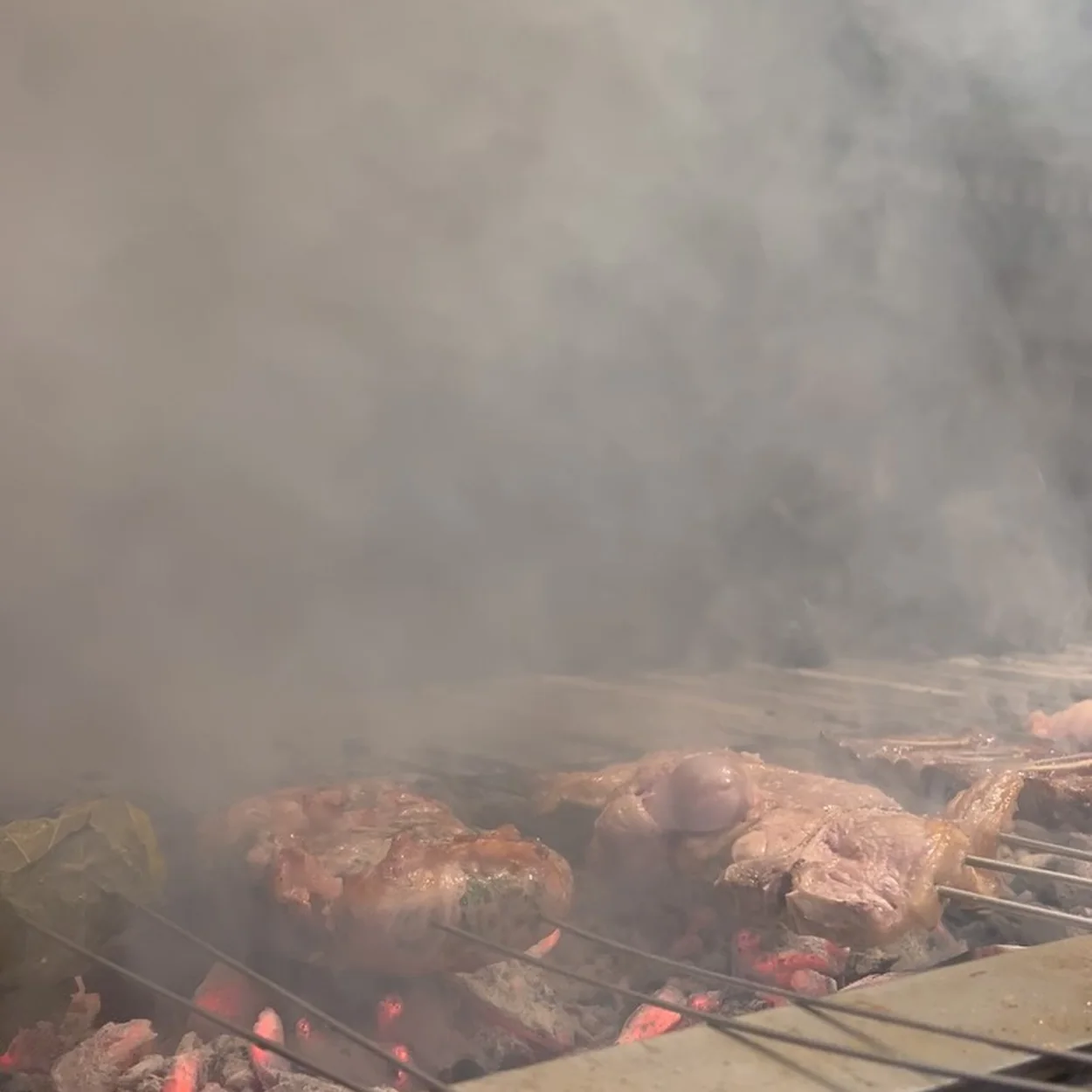 Smoke rising off cuts of meat on the live-fire grill at Impala Soho