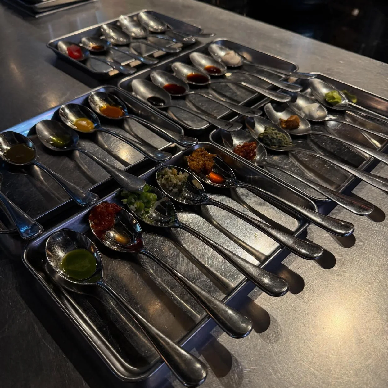 Rows of tasting spoons laid out on the pass at Impala Soho