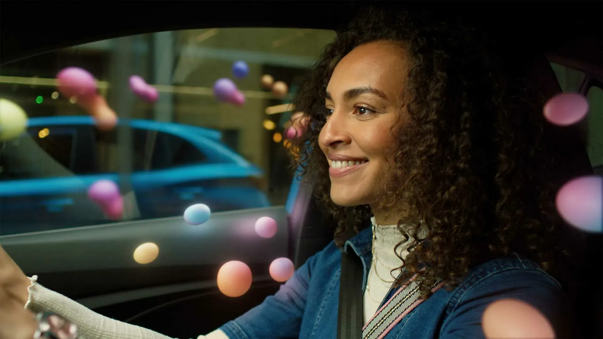 Frame from Lambda Films MG Motors TV commercial showing a smiling driver surrounded by colourful animated spheres