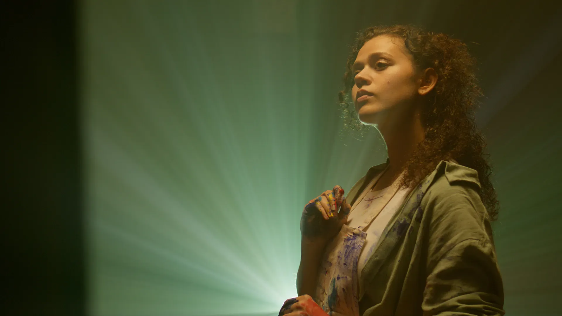 Cinematic frame from a Lambda Films WIPO production with an artist lit by a green projector beam