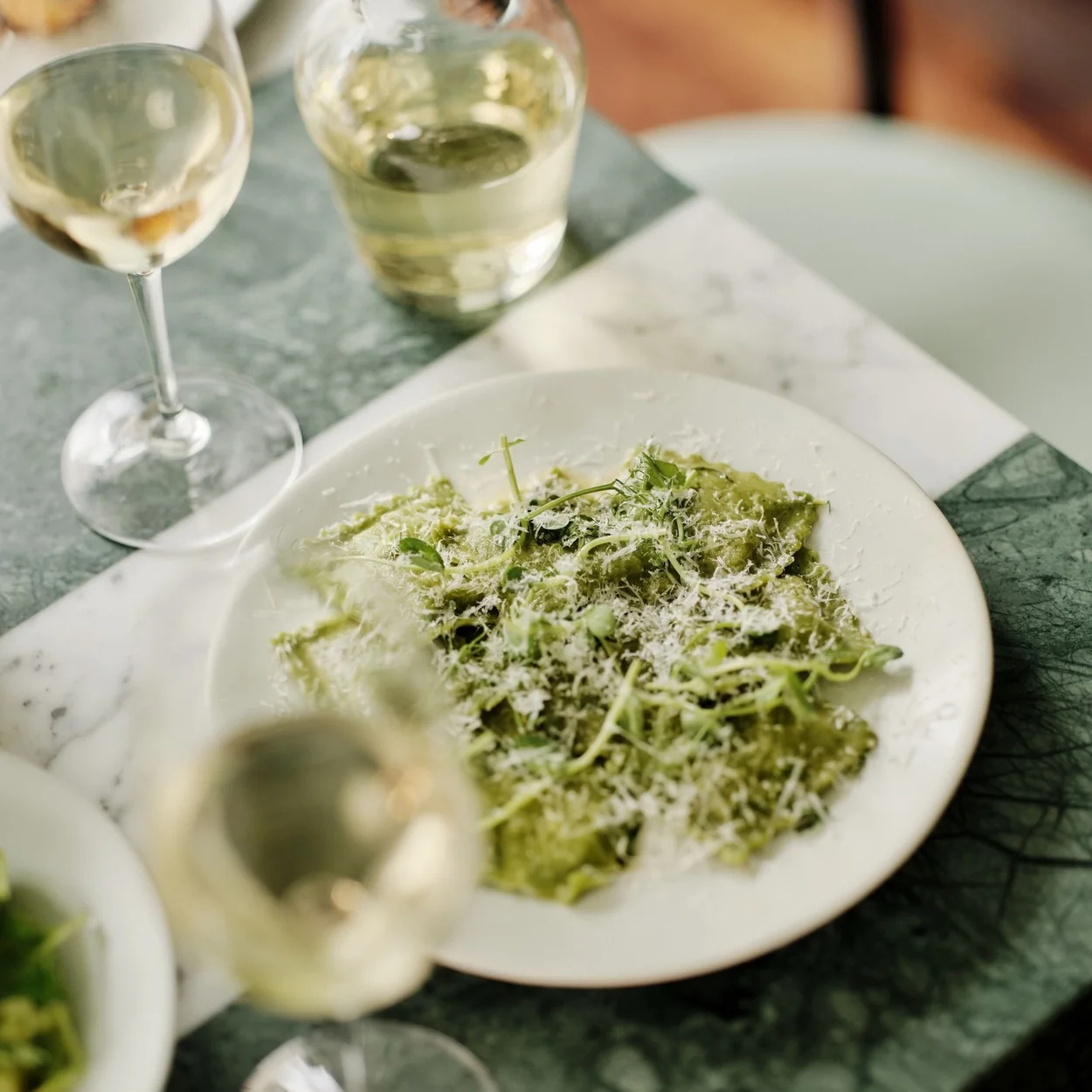 Dressed green salad and glasses of white wine on the marble counter at Lina Stores
