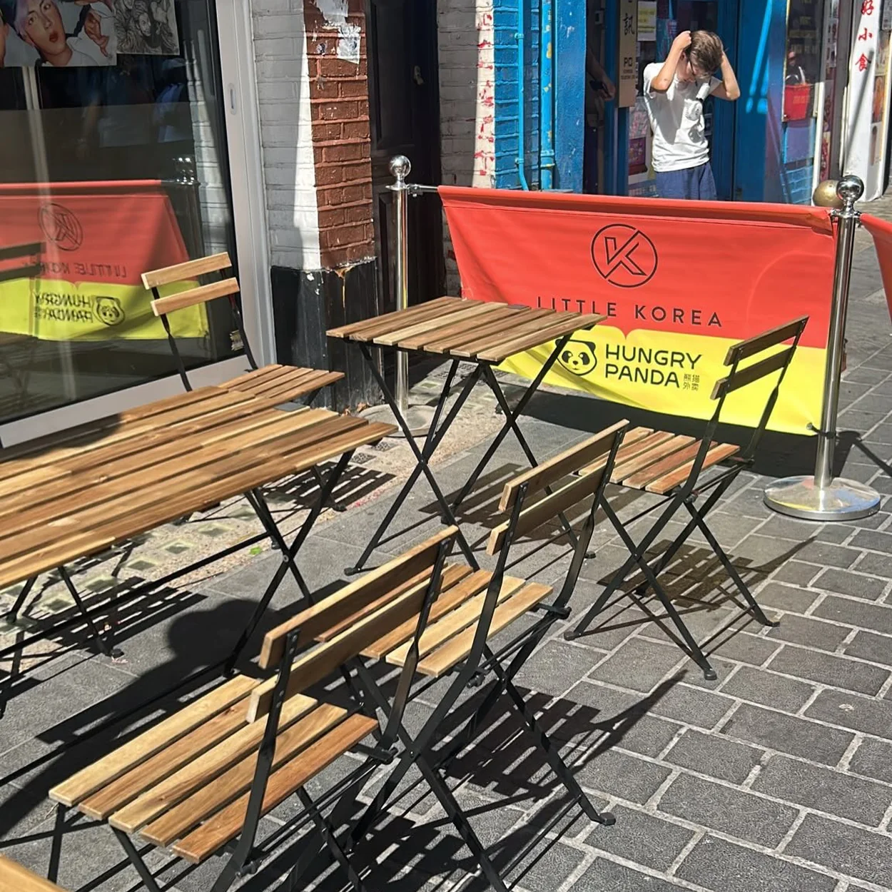 Terrace tables and branded barriers outside Little Korea on Lisle Street