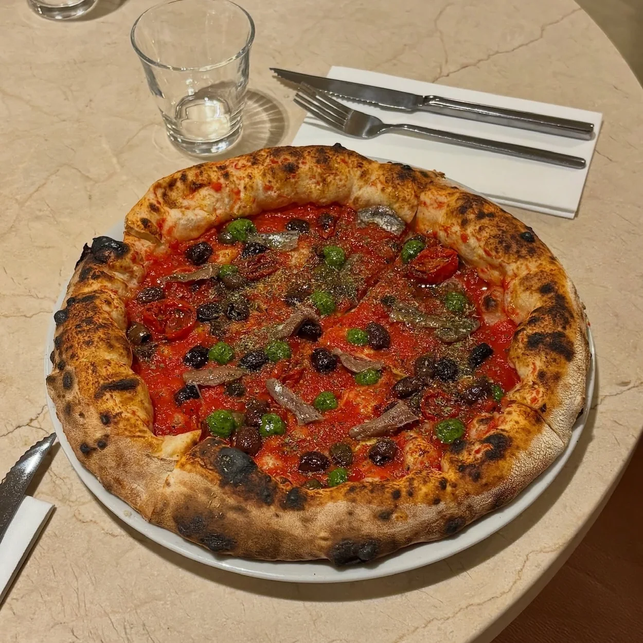 Wood-fired Neapolitan pizza with olives on the marble counter at Napoli on the Road in Soho