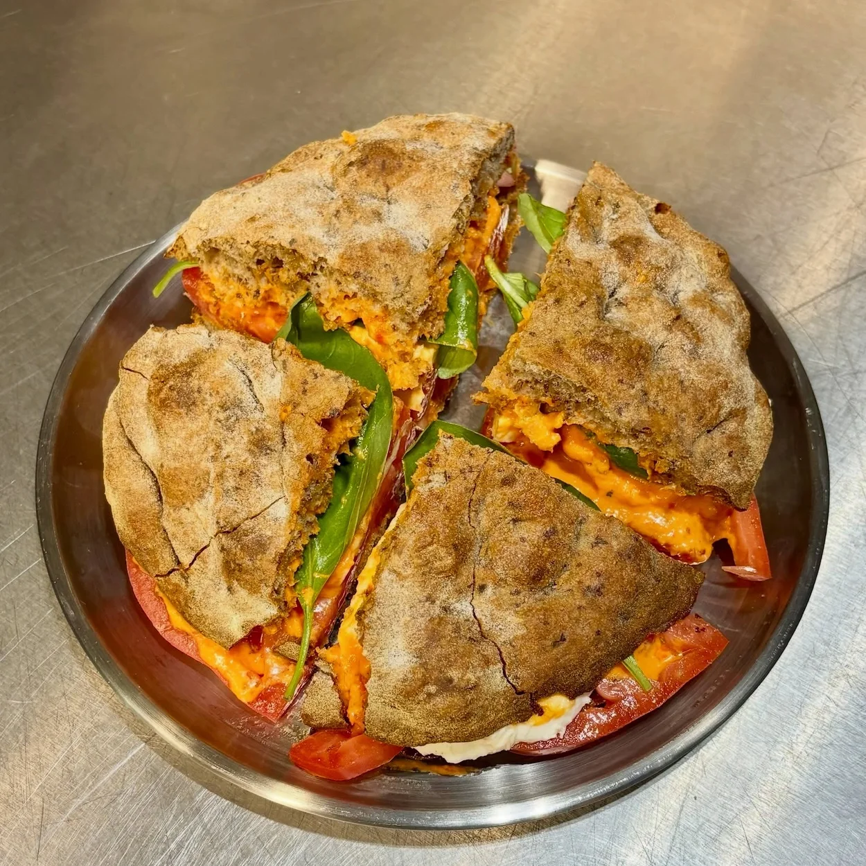 Stuffed panuozzo sandwich quartered on a steel tray at Napoli on the Road Soho
