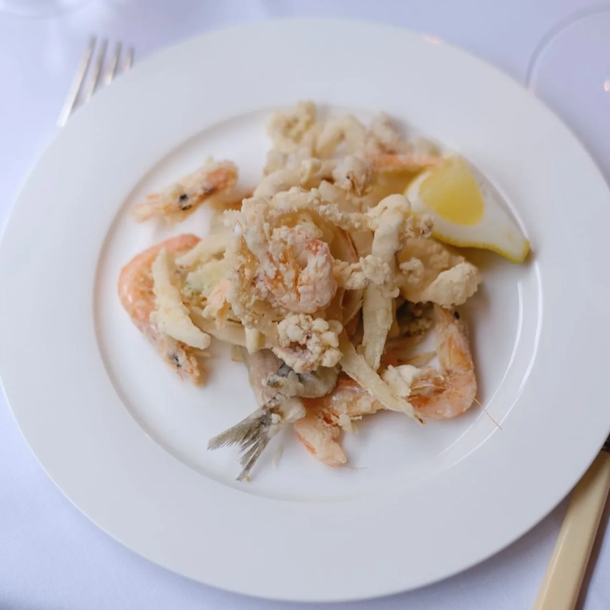 Fritto misto with prawns and lemon on a white plate at Osteria Vibrato in Soho