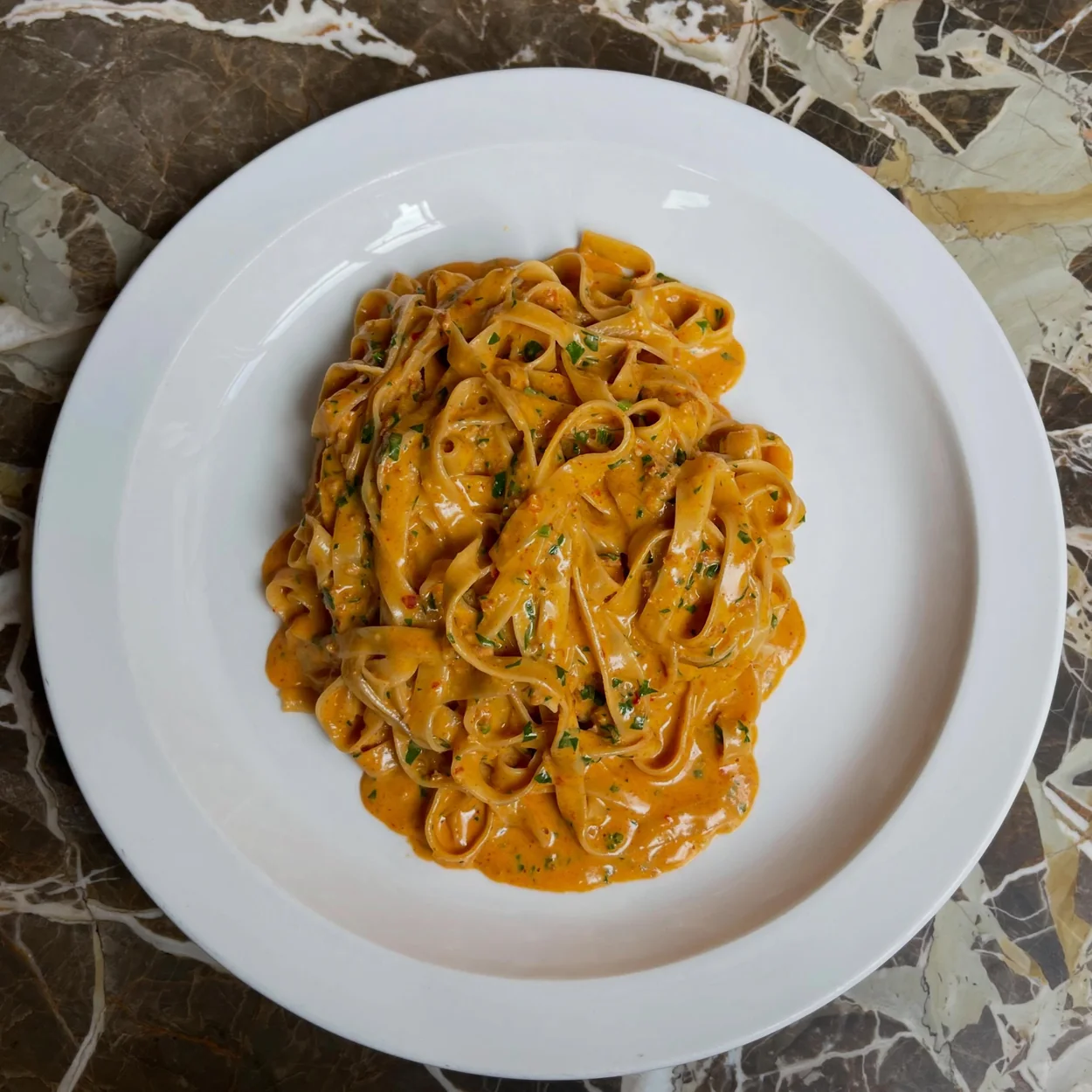 Hand-rolled pasta ribbons in a rich tomato sauce on a Padella plate
