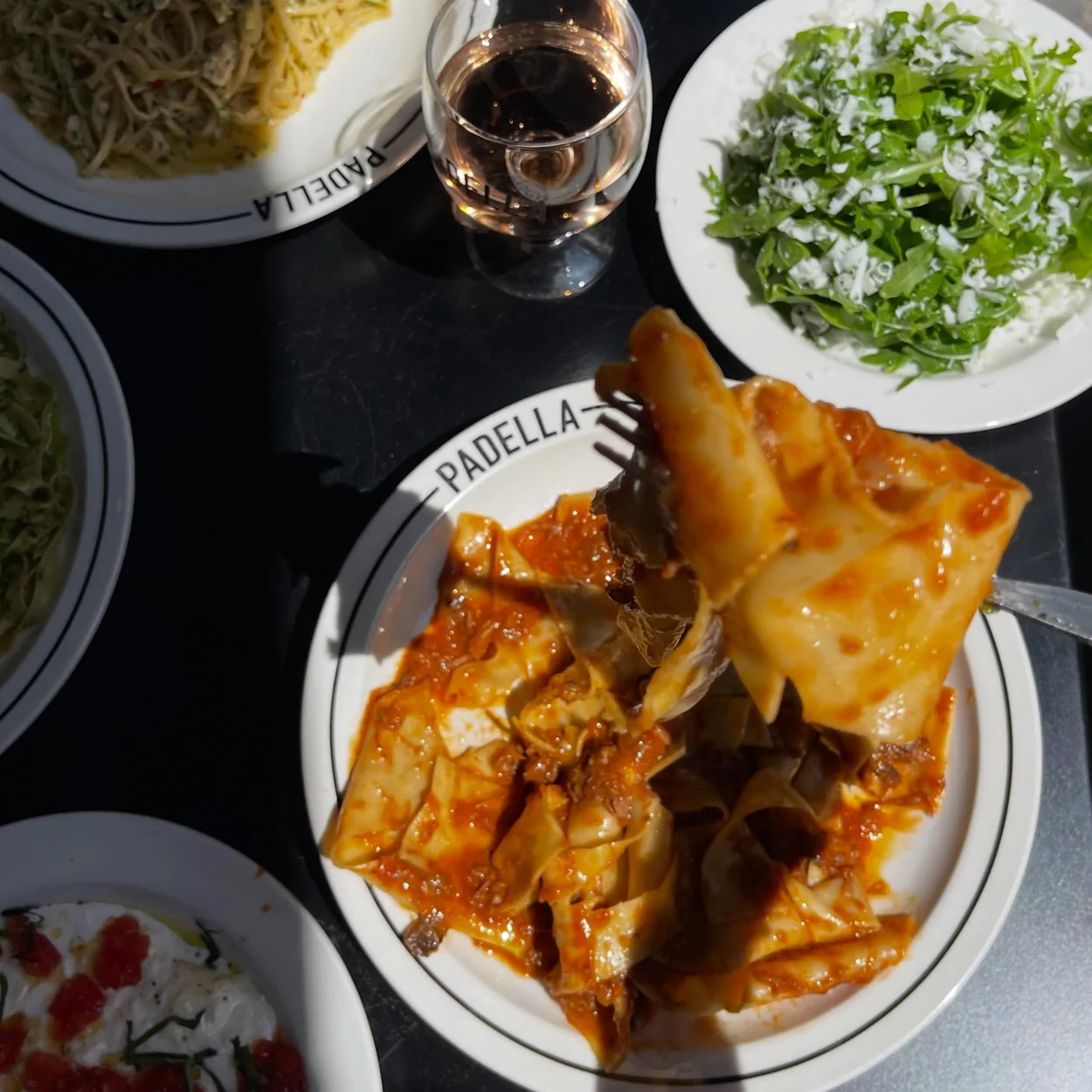 Table of pasta dishes, salad and wine in Padella's Soho dining room