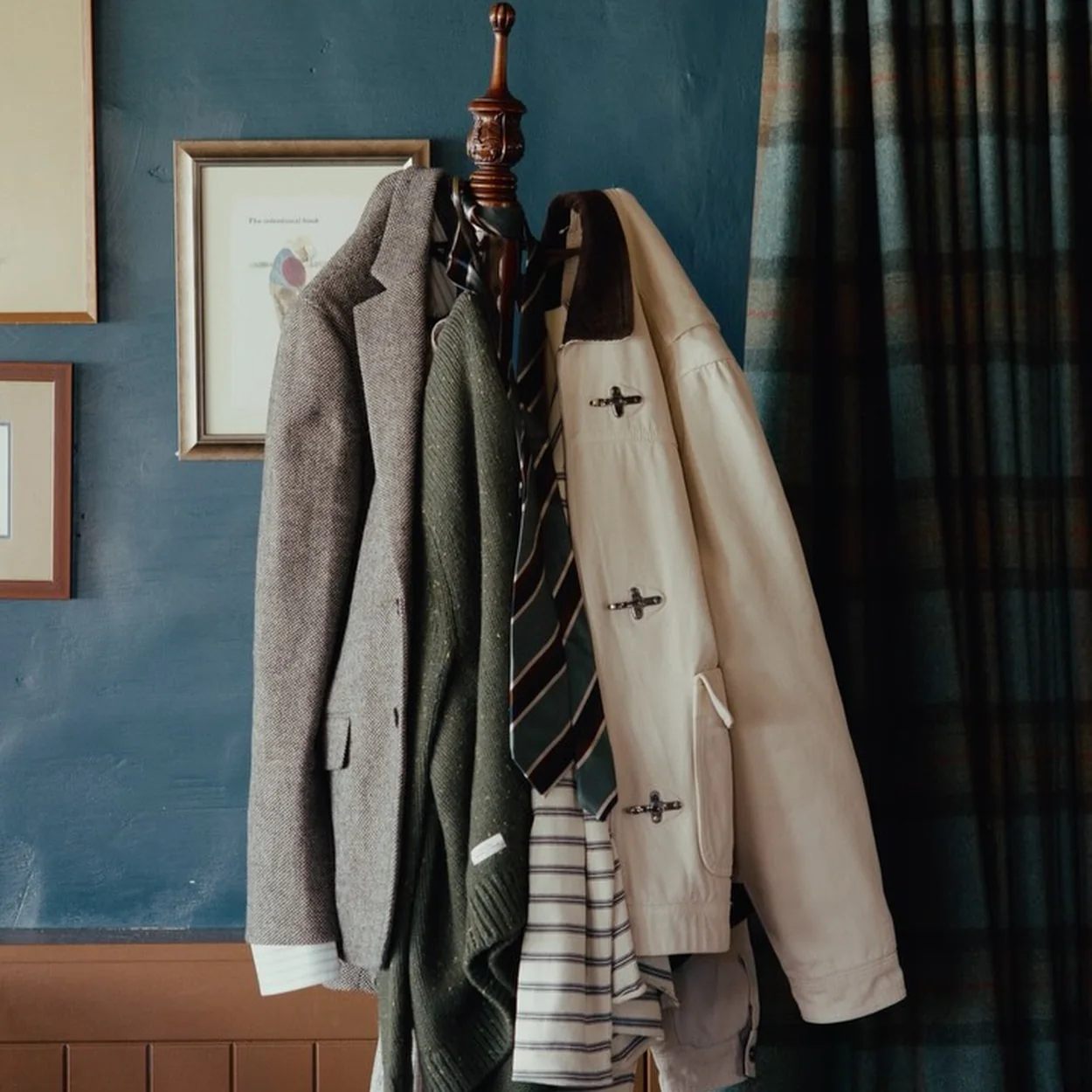 Coats and knitwear layered on a rack at Percival, the London menswear label in Soho