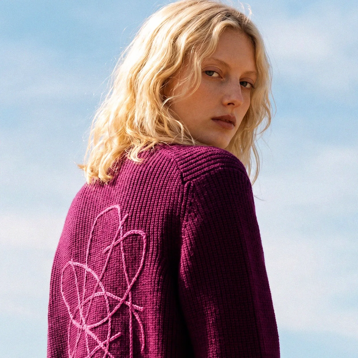 Shoulder detail of a berry-tone Sheep Inc knit worn on the beach