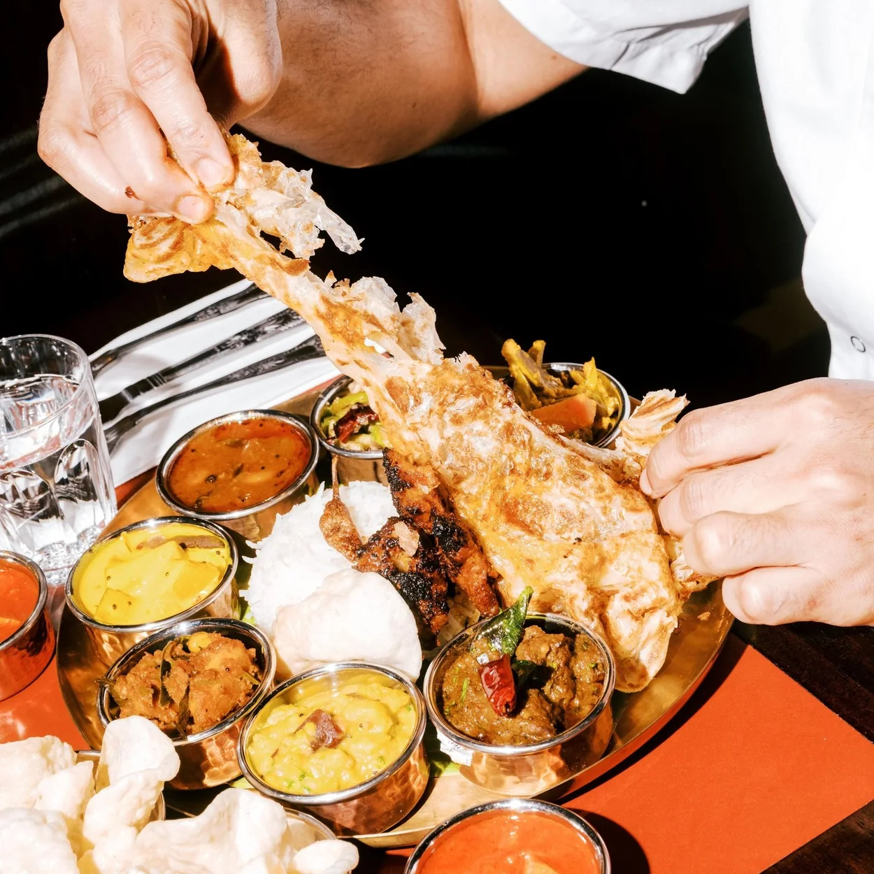 Tearing dosa over a South Indian thali of curries and chutneys at Tamila in Soho
