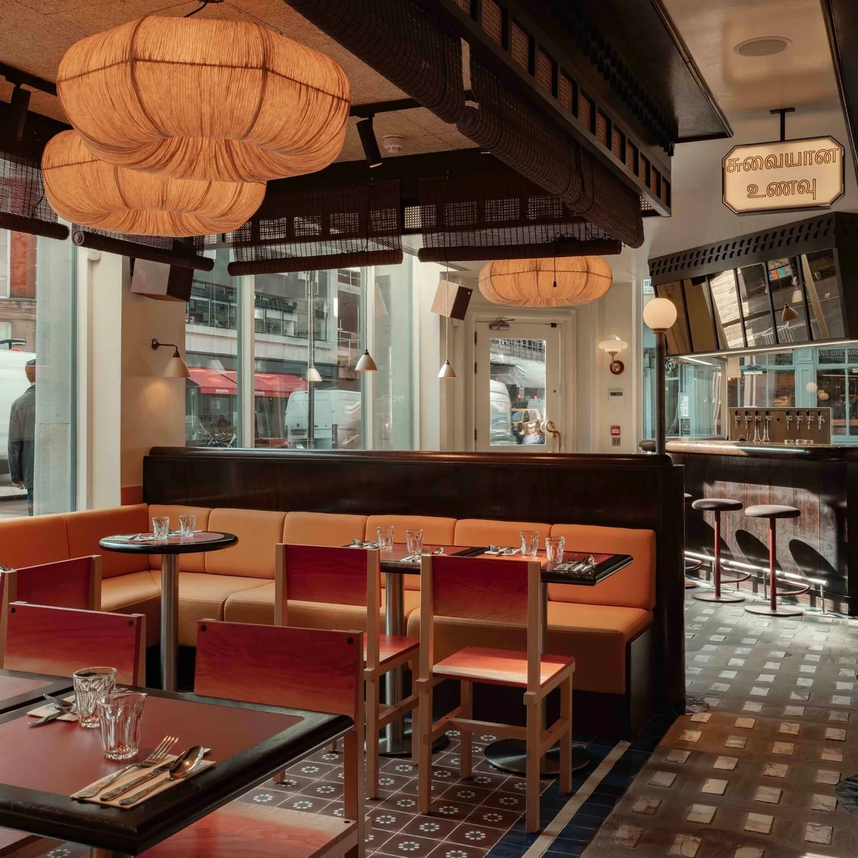 Red banquettes and rattan lamps in the dining room at Tamila, Soho's Tamil restaurant