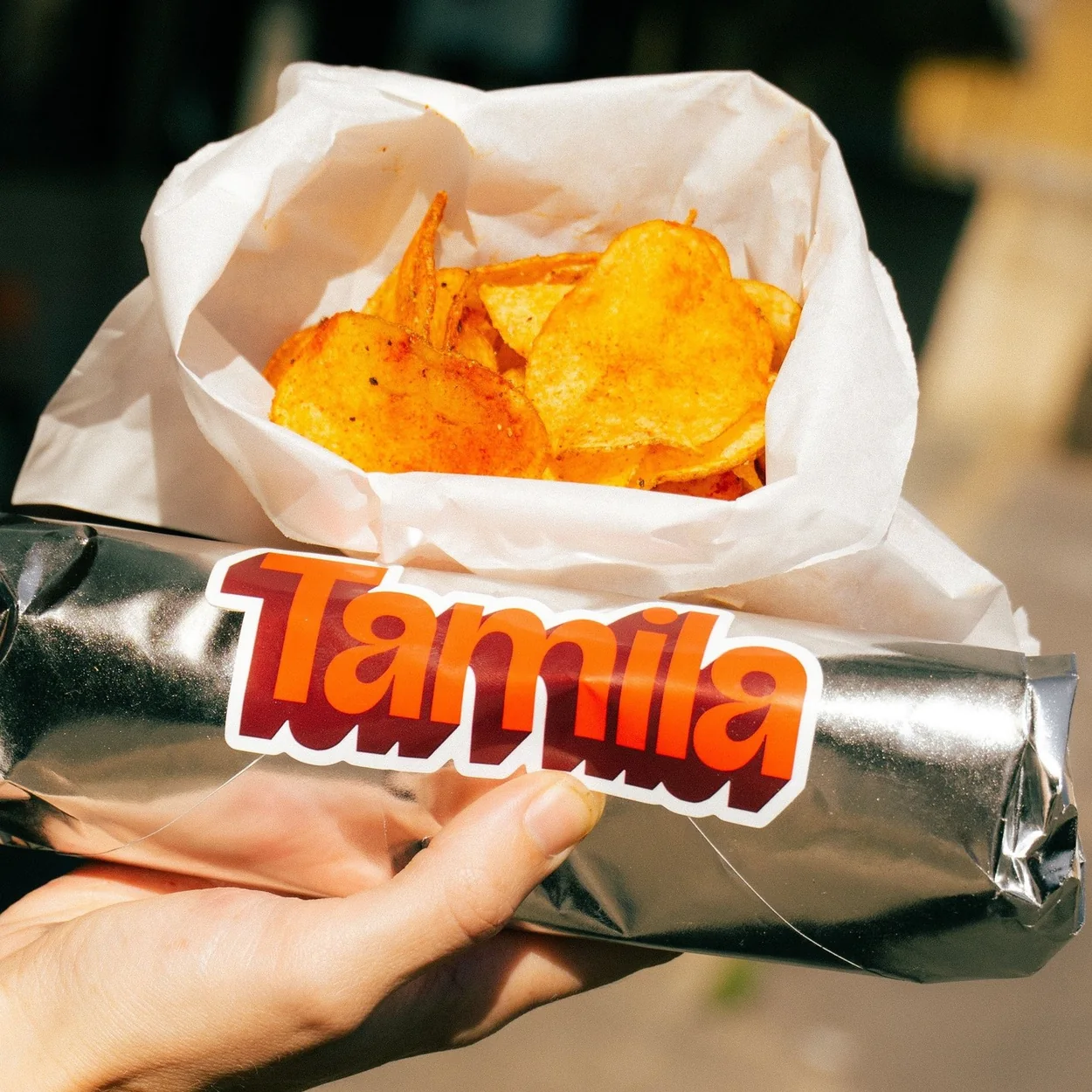 Foil-wrapped Tamila roll with a bag of crisps held outside the Soho restaurant