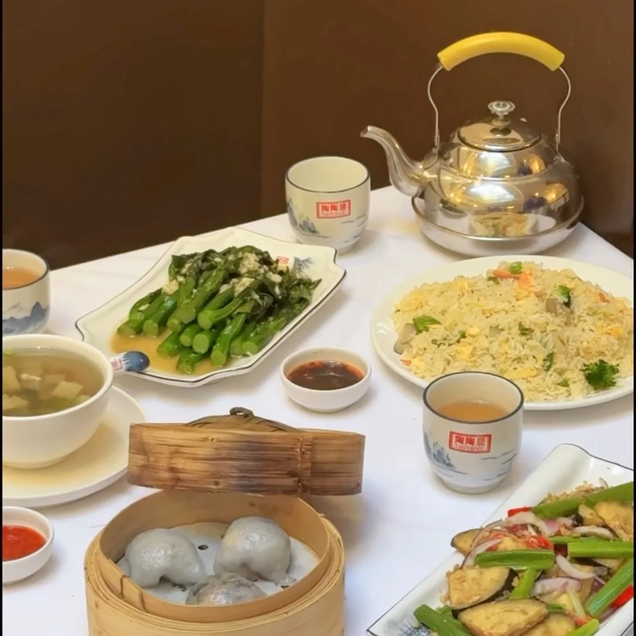 Dim sum table with teapot, fried rice and greens at Tao Tao Ju
