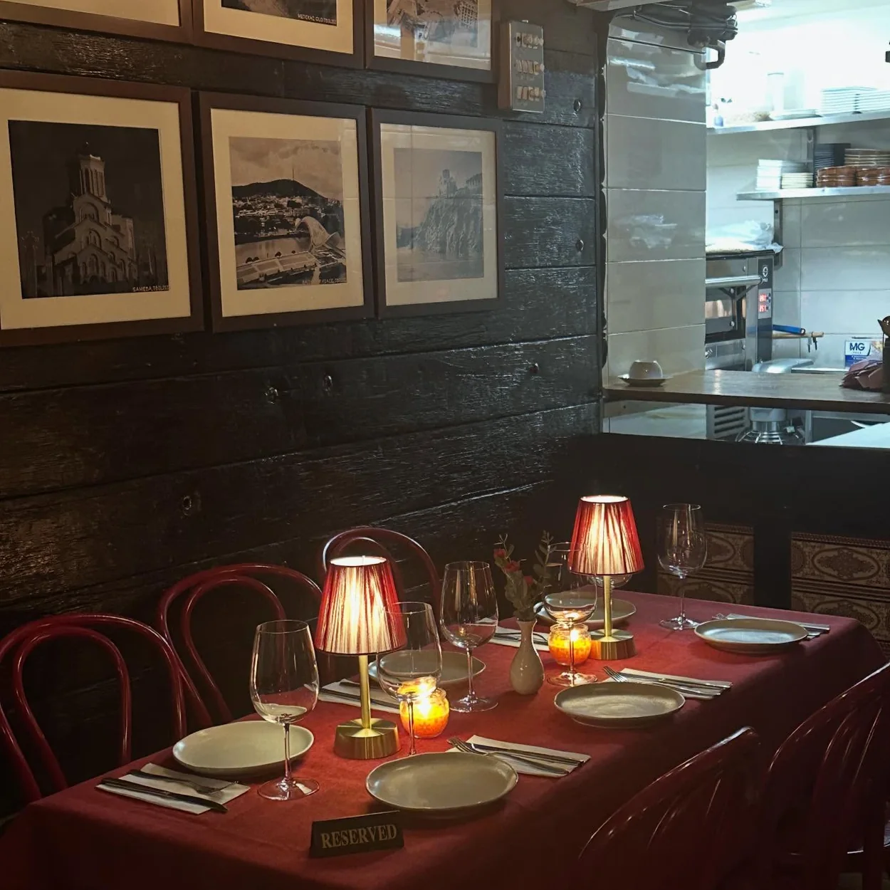 Lamplit tables set with red cloths in the dining room at Violet's Soho
