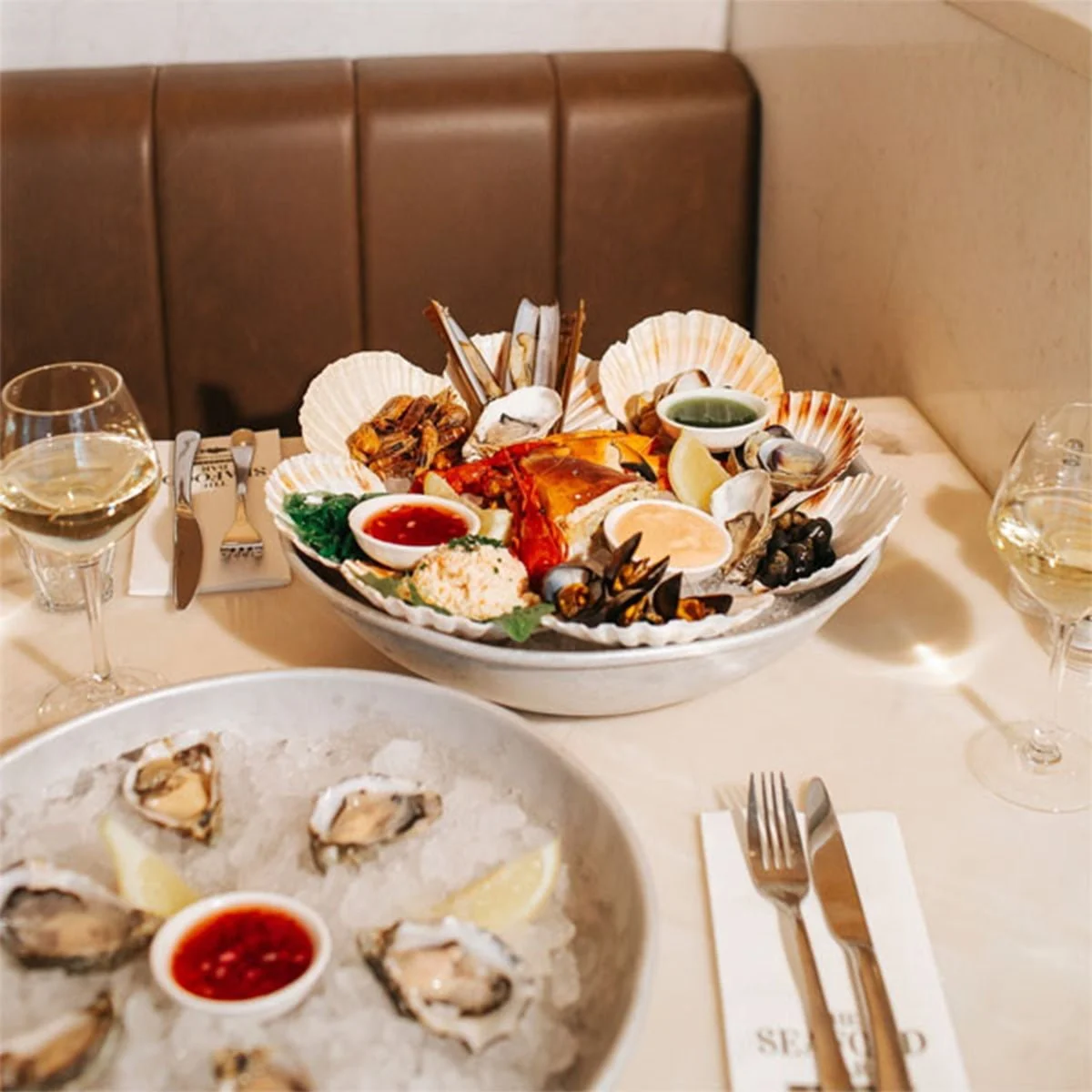 Seafood platter of lobster, razor clams, mussels and scallops with oysters on ice at a booth table in The Seafood Bar, Soho