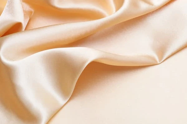 Close-up of cream silk twill fabric showing its lustre and drape