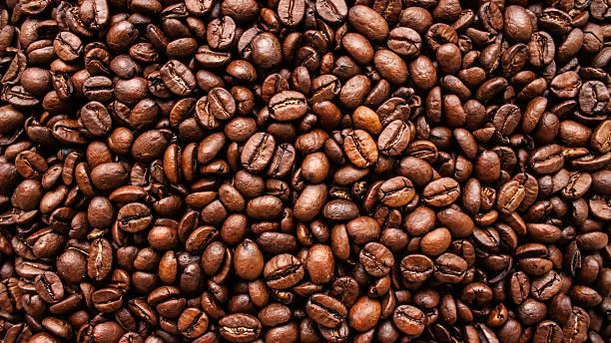 A dense layer of glossy dark roasted coffee beans filling the frame